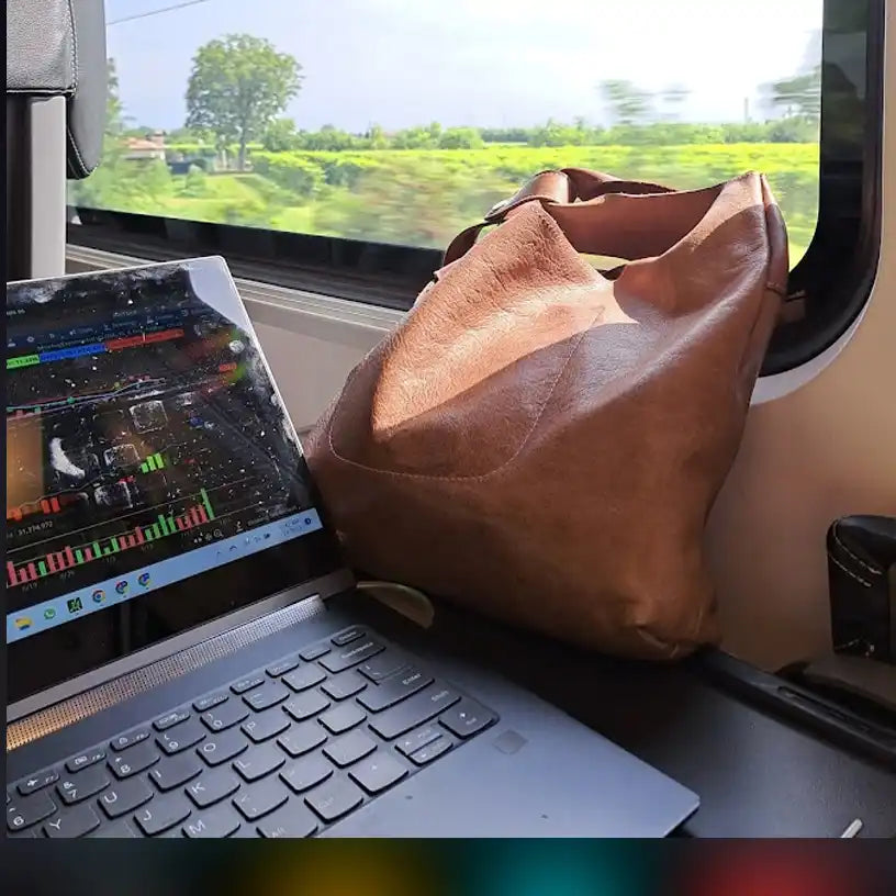 Brown leather handbag resting on a laptop keyboard.