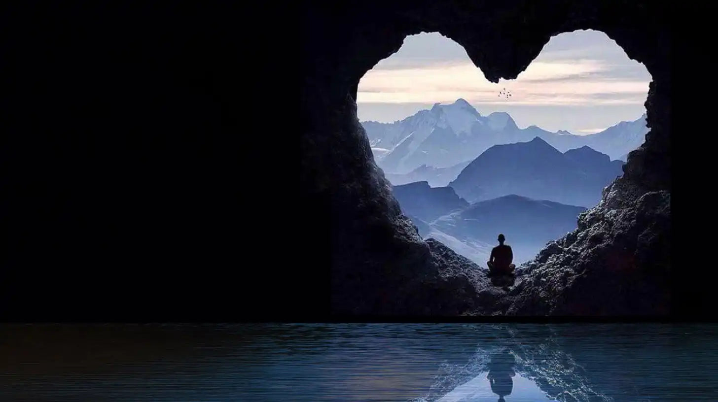 Heart-shaped cave opening framing a silhouetted figure and mountain vista.